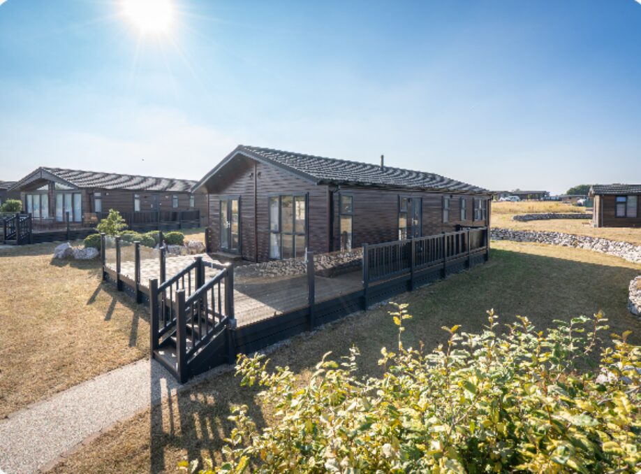 Holiday lodge for sale on a UK holiday park with wraparound decking on a sunny day.